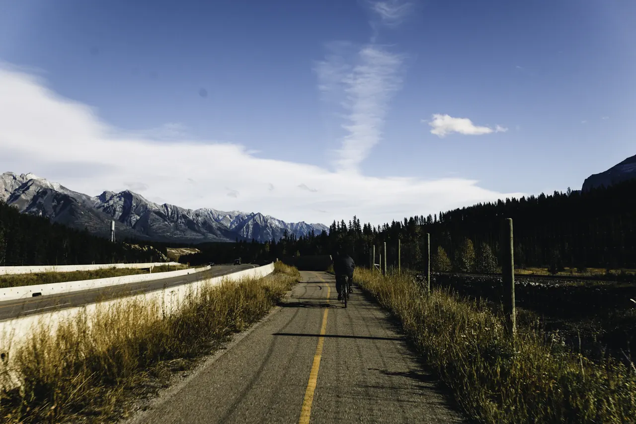 Cyclists heading toward the Canadian Rockies on a sunlit cycle path